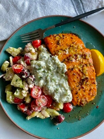 greek salmon plated with tsatziki and chopped greek salad